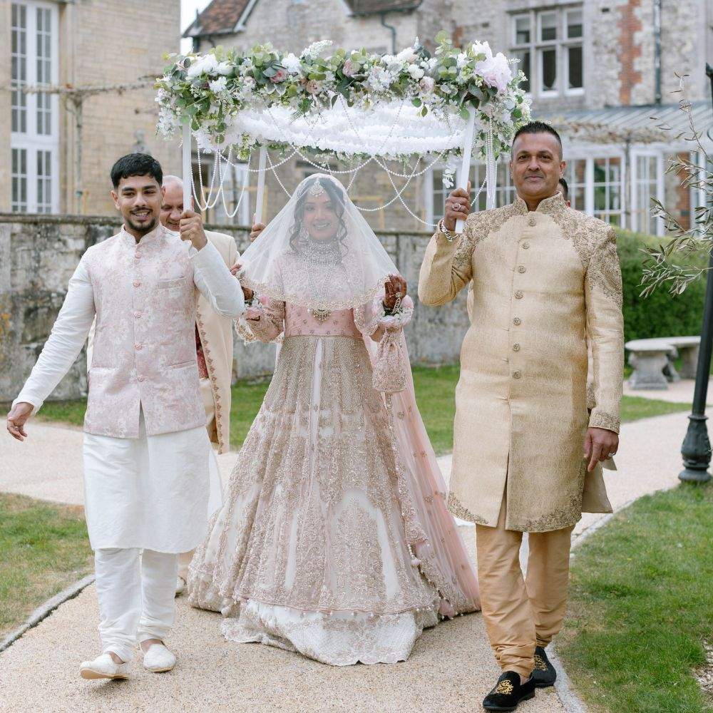 A Bride being walked down the aisle by family members during their Muslim wedding ceremony at Russets, a Pakistani Wedding Venue near London